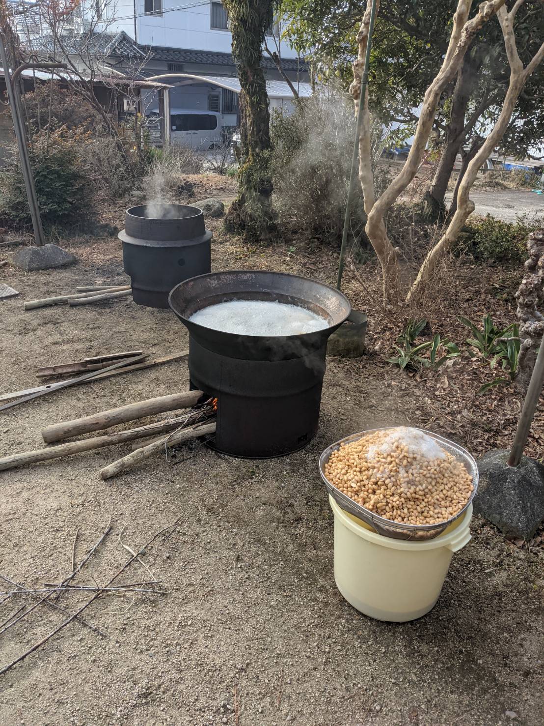 屋外の釜と、ざるに盛られた豆